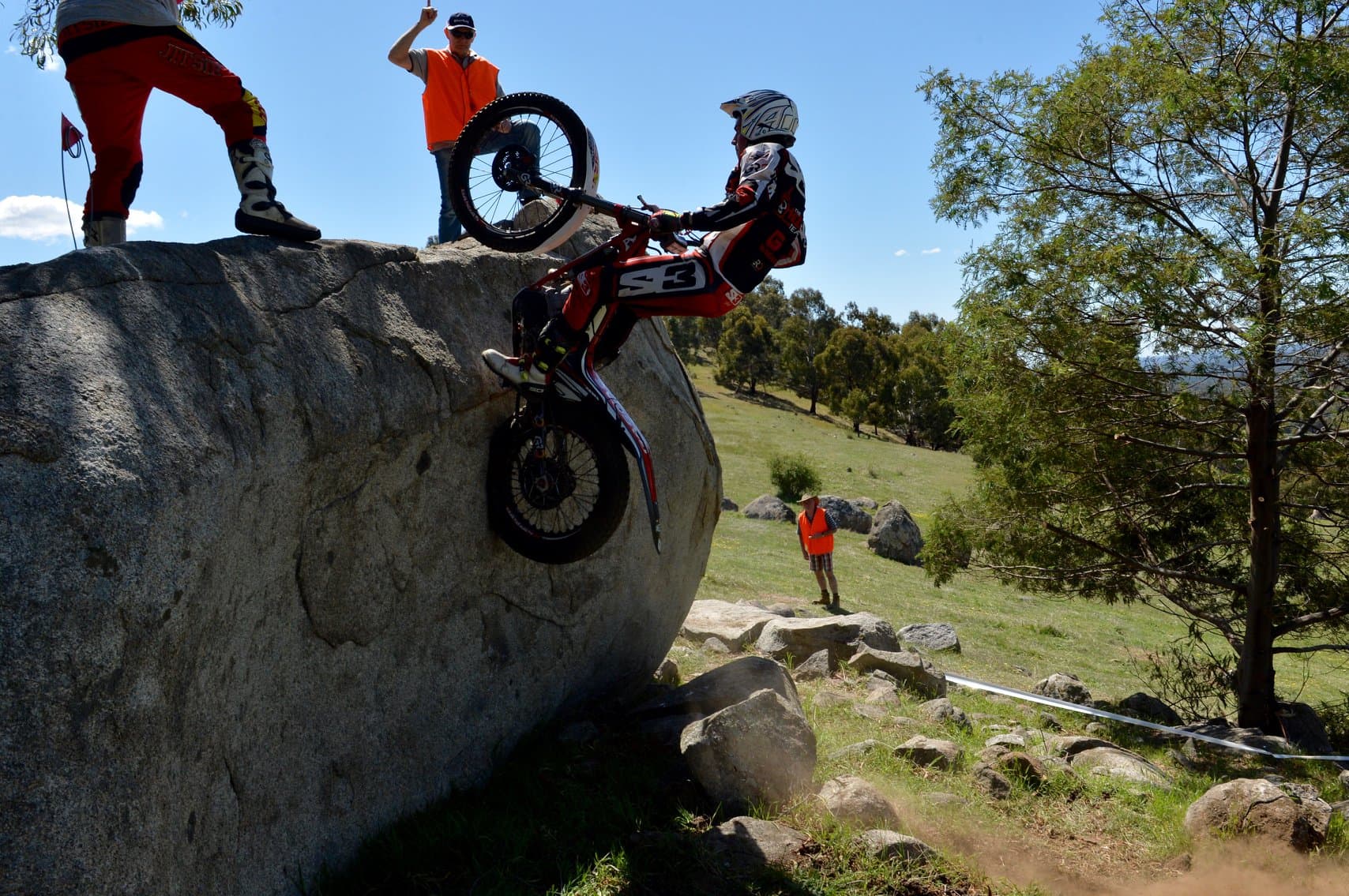 Motorcycle trials rider navigating massive boulders at an Australian competition